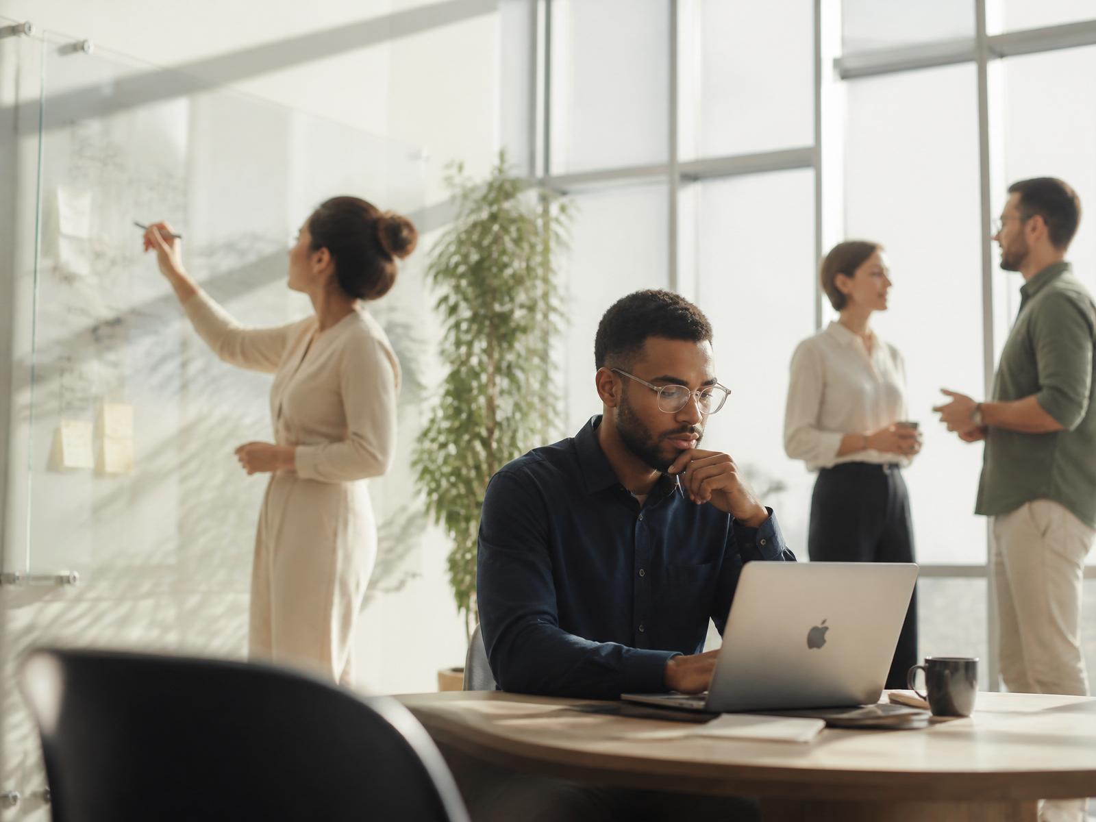 Diverse young professionals collaborating in a calm, sunlit modern workspace